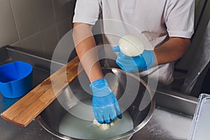 Artisan cheesemaker cuts the mozzarella with hands.