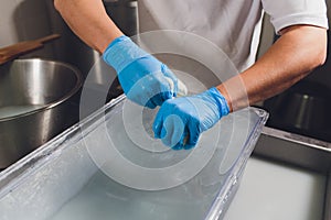 Artisan cheesemaker cuts the mozzarella with hands.