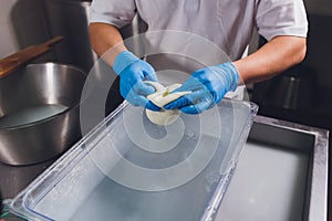 Artisan cheesemaker cuts the mozzarella with hands.