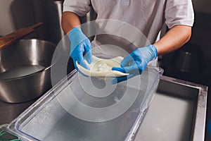 Artisan cheesemaker cuts the mozzarella with hands.