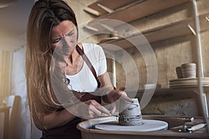 Artisan creatively shaping a vase turning on her pottery wheel