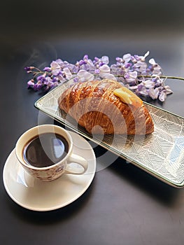 artisan croissant, cornetto with cream, purple wisteria, pink background, cup with coffee, small espresso, black background