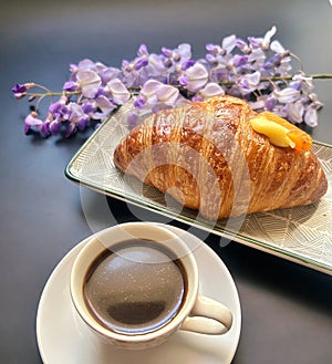 artisan croissant, cornetto with cream, purple wisteria, pink background, cup with coffee, small espresso, black background