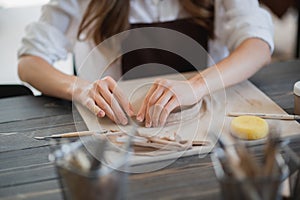 Artisan female potter prepares material for her pottery. Woman hands attach clay part to future ceramic product. Work