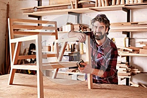 Artisan furniture designer sanding a chair in his workshop