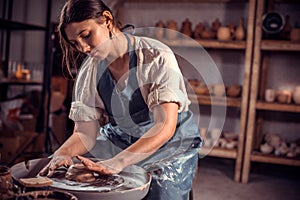 Artisan girl is working on pottery wheel. The concept of craft creativity. Close-up.