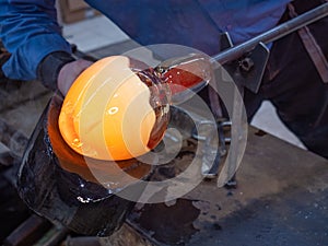 Artisan hands working with hot malleable glass on glassblower whistle