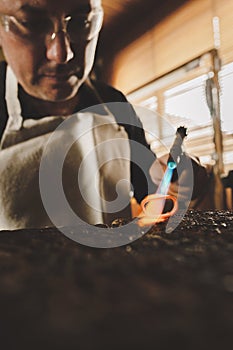 artisan man in the process of manufacturing a jewel molding ring with fire in his workshop