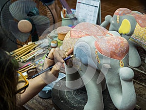 Artisan painting a clay elephant with hands