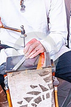 Artisan, scoring a design on metal strip, with hammer