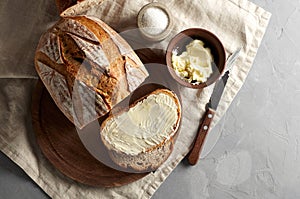 Artisan sliced toast bread with butter and sugar on wooden cutting board. Simple breakfast on grey concrete background