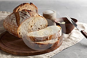 Artisan sliced toast bread with butter and sugar on wooden cutting board. Simple breakfast on grey concrete background