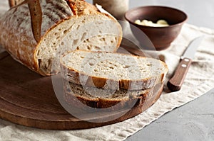 Artisan sliced toast bread with butter and sugar on wooden cutting board. Simple breakfast on grey concrete background