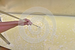 Artisanal cheese making, cutting the curd and whey in the factory tank