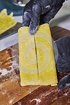 Splitting Fresh Homemade Pappardelle Pasta by Gloved Hands photo