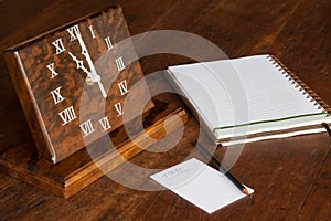 Artisanal wooden clock on the table, with paper to notations