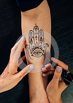Artist applying henna mehndi tattoo on female hand