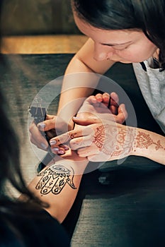 Artist applying henna mehndi tattoo on female hand