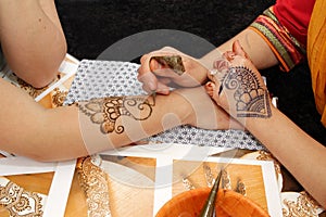 Artist applying henna tattoo on women hands