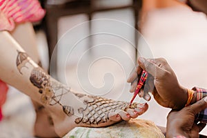 Artist applying henna tattoo on women hands.