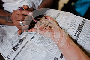 Artist applying henna tattoo on women hands.