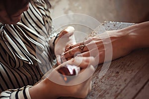 Artist applying henna tattoo on women hands