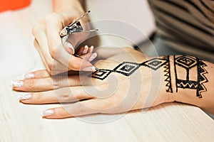 Artist applying henna tattoo on women hands. Mehndi is traditional Indian decorative art. Close-up