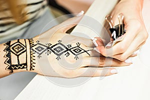 Artist applying henna tattoo on women hands. Mehndi is traditional Indian decorative art. Close-up