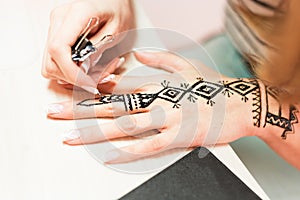 Artist applying henna tattoo on women hands. Mehndi is traditional Indian decorative art. Close-up