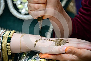 Artist applying henna tattoo on women hands. Mehndi is traditional moroccan decorative art.