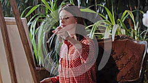 Artist in an art studio with plants - young pretty woman drawing a greek head sculpture on a canvas