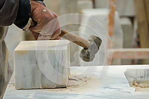 artist chiseling marble block with mallet