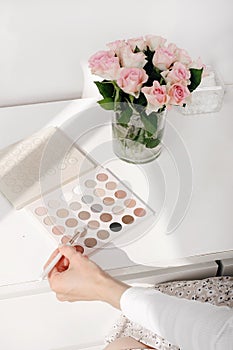 Artist choosing Cosmetics for make-up on color palette with foundation