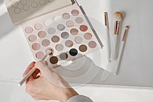 Artist choosing Cosmetics for make-up on color palette with foundation