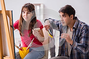 The artist coaching student in painting class in studio