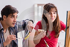 Artist coaching student in painting class in studio