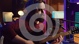 Artist with condenser microphone composing a song on guitar