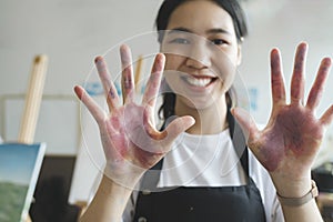 The artist creates a frame with her hands soiled with watercolor paints.