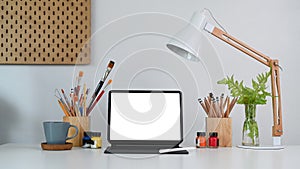 Artist or creative designer workplace with tablet and drawing equipment on white table.