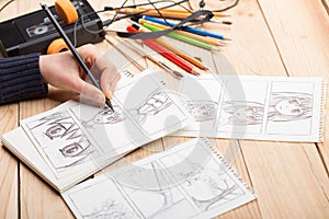 Artist drawing an anime comic book in a studio. Wooden desk, natural light. Creativity and inspiration concept