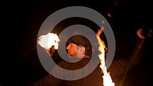 Artist of the fire show spinning fireballs around itself. Close up. Slow motion