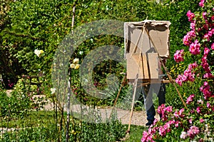 Artist in garden painting with an easel.