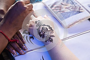 Artist grafting temporary henna mehendi tattoo art onto hand fin