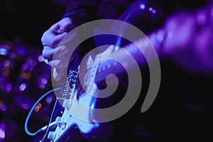 Artist Guitarist hand play electricity guitar on concert stage with blue light, Practicing in playing . song