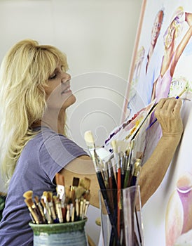 Artist in her fifties painting on canvas