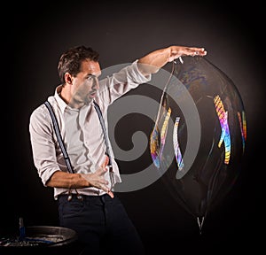 Artist hold big soap bubble in his hands.