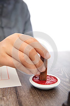 The artist holds a seal in his hand and stains it with red ink