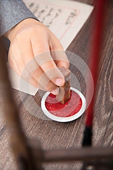 The artist holds a seal in his hand and stains it with red ink