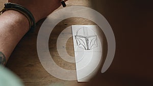 The artist makes a sketch on a piece of paper. Close-up of a hand with a pencil. wood carver draws a sketch for wood carving.