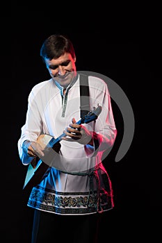 Artist musician A brunette man in a folk shirt playing a balalaika